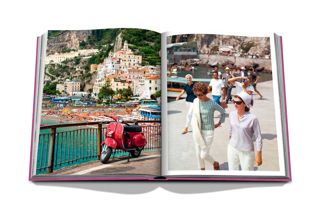 In an open Amalfi Coast book by Assouline, the left page showcases a coastal town along the breathtaking côte Amalfitaine with vibrant buildings, a beach, and a red scooter; the right page captures three women in summer outfits strolling outside against a scenic backdrop of water and rocky cliffs, ideal for panoramic hikes.